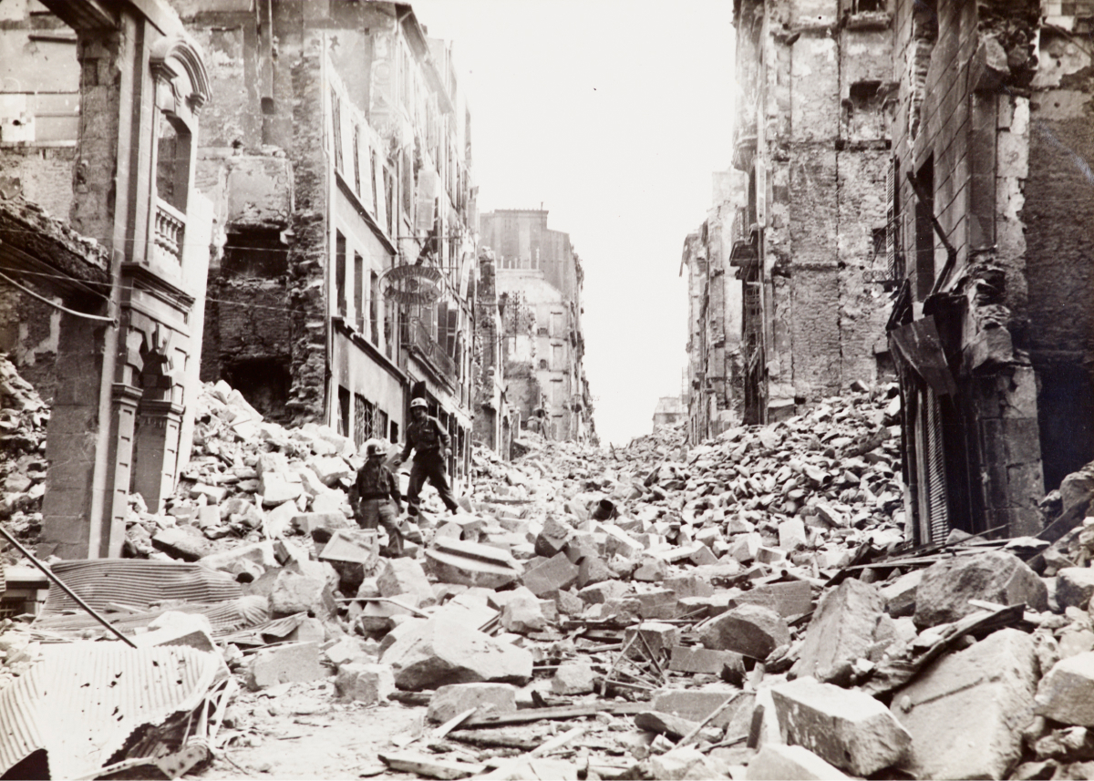 Septembre 1944 à Brest. Vue de la rue Jean Macé détruite. Deux soldats se déplacent parmi les ruines. 